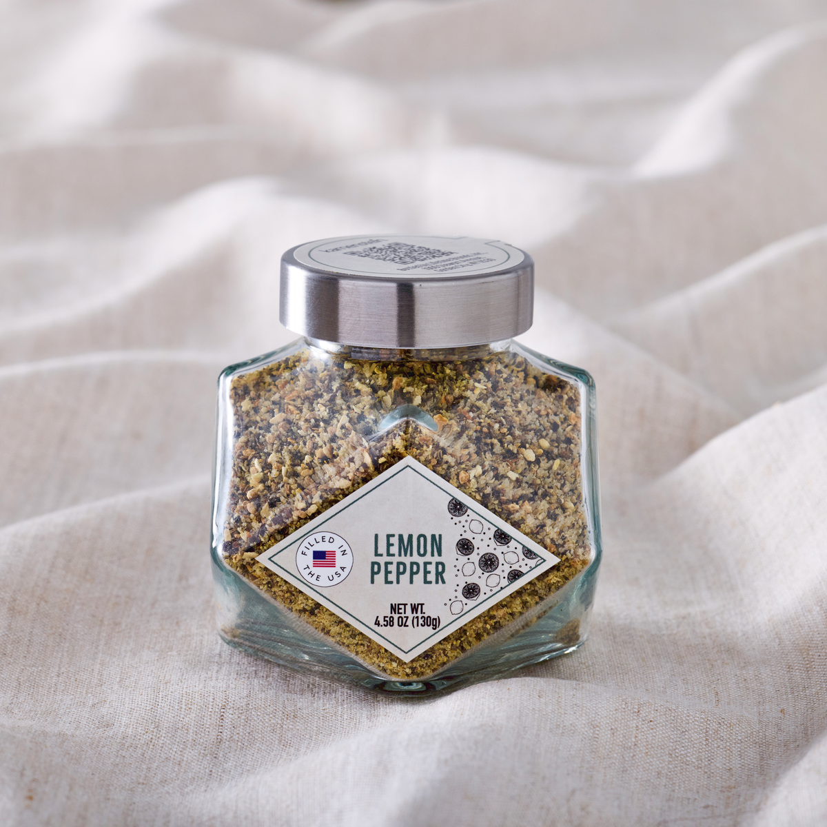 Close up of a glass Diamond Jar lemon pepper seasoning bottle with a silver cap