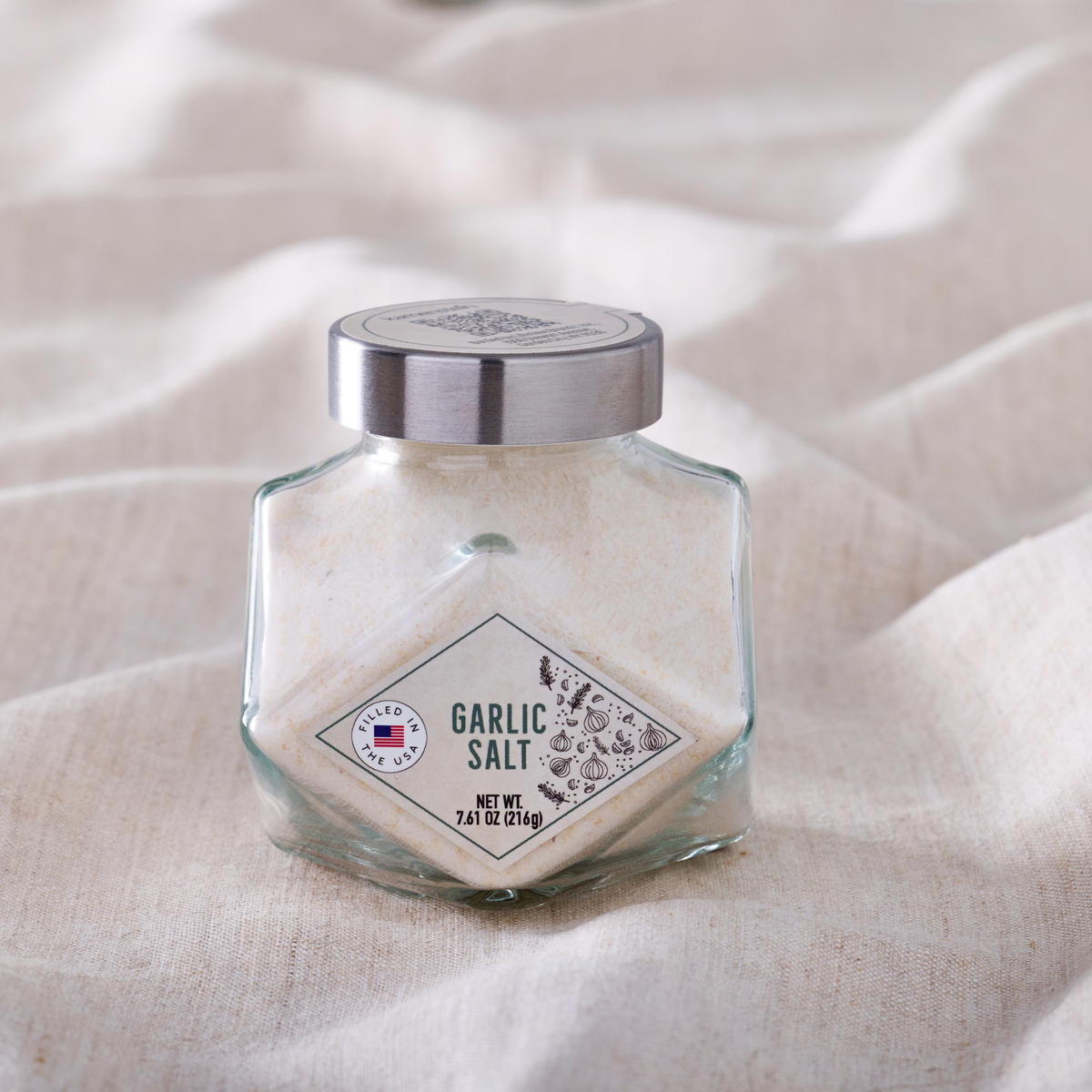 Garlic salt in a clear glass jar with a silver metal lid and a visible front label
