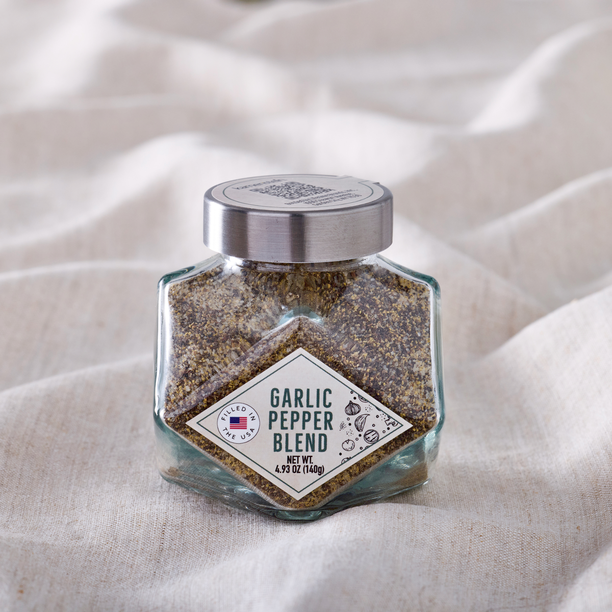 Diamond jar glass spice bottle filled with garlic pepper blend and a silver lid